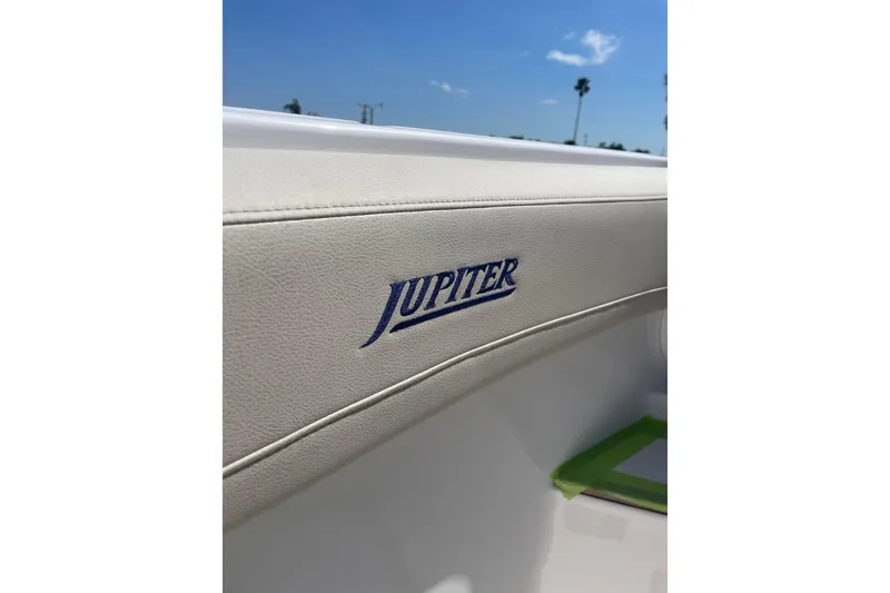 Slide: The Image of 2025 Jupiter 43 boat interior with logo, featuring sleek white upholstery under a clear blue sky. - 23
