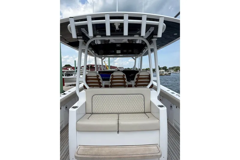 Slide: The Image of 2025 Jupiter 43 boat interior with cushioned seating and helm, docked by the water. - 36