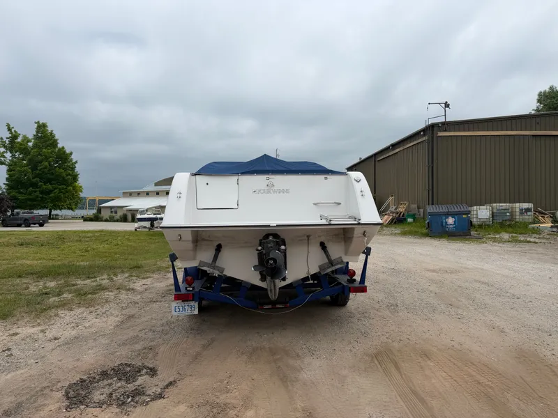 Slide: The Image of A 1992 Four Winns 225 Sundowner on a trailer, parked on a gravel lot. - 2