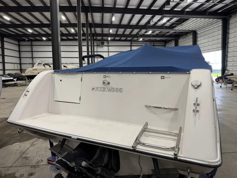Slide: The Image of The image shows the stern of a 1992 Four Winns 225 Sundowner with a blue cover in a storage facility. - 8