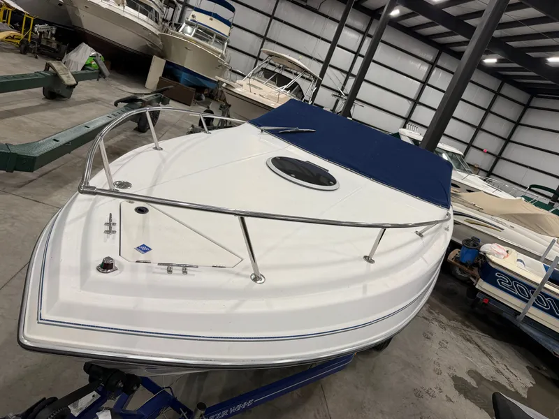 Slide: The Image of A 1992 Four Winns 225 Sundowner in a storage facility, featuring a blue cover and stainless steel railing. - 5