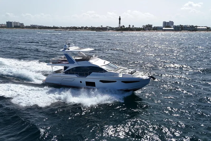 Slide: The Image of 2021 Azimut Fly 60 yacht cruising on the ocean near a coastal cityscape. - 70
