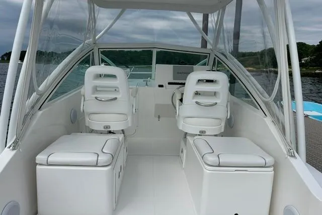 Slide: The Image of 2019 Albemarle 25 Express boat interior with white seating and clear canopy on the water. - 20