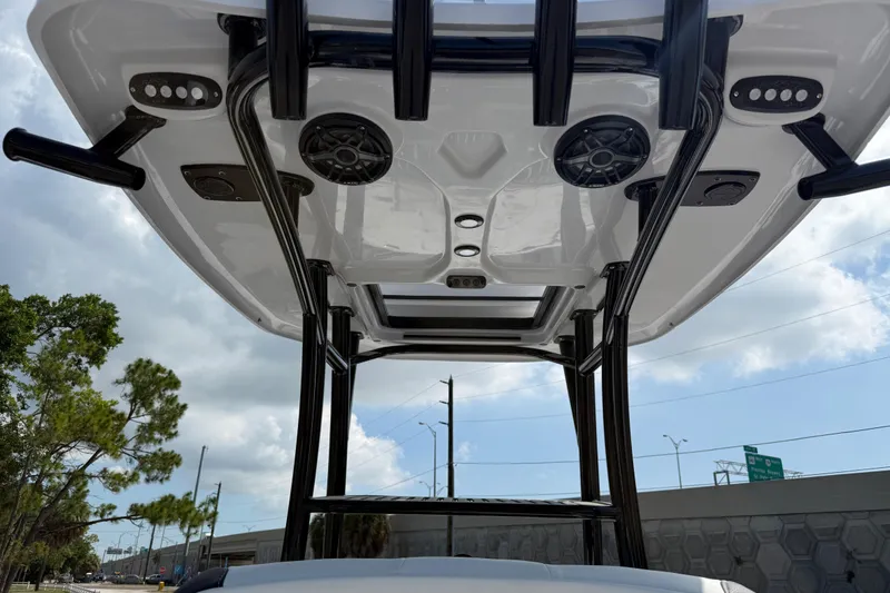 Slide: The Image of Tidewater 2500 Carolina Bay 2027 boat T-top with speakers and rod holders under cloudy sky. - 10