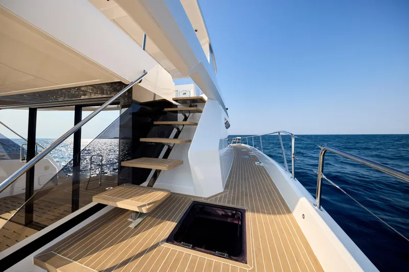 Slide: The Image of 2025 Custom Omaya 50 Power Catamaran deck with ocean view, featuring modern design and wooden steps. - 11