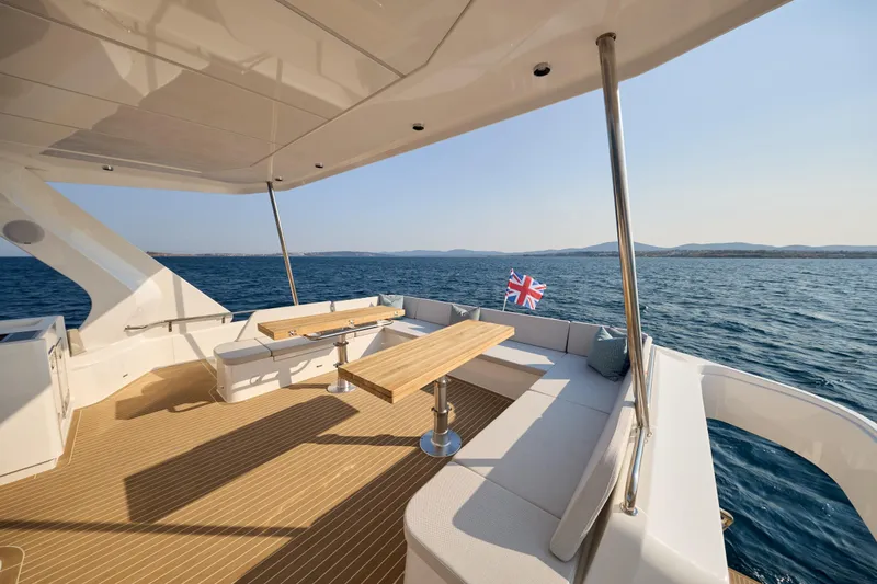 Slide: The Image of Luxurious 2025 Omaya 50 Power Catamaran deck with seating, ocean view, and flag. - 39