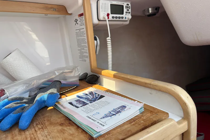 Slide: The Image of Interior of 2015 Catalina 275 Sport sailboat with manual, gloves, and radio equipment. - 39