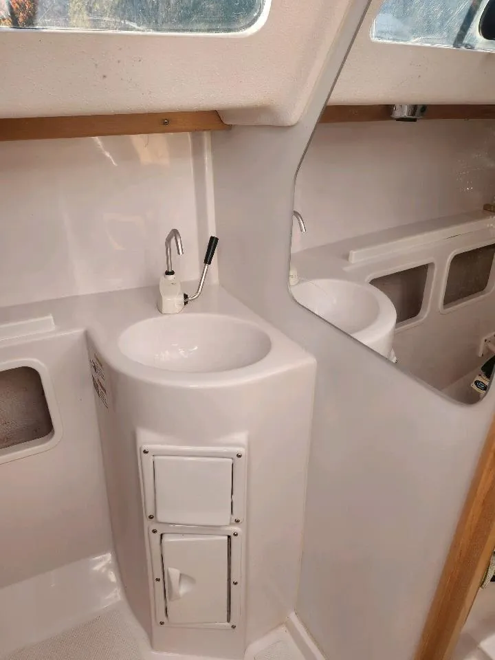 Slide: The Image of The image shows a white bathroom on a boat with a sink and mirror. - 29