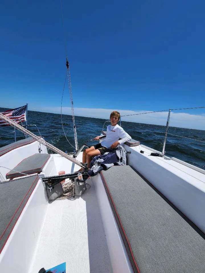 Slide: The Image of A boy sits on a sailboat on the sea under a clear sky. - 17