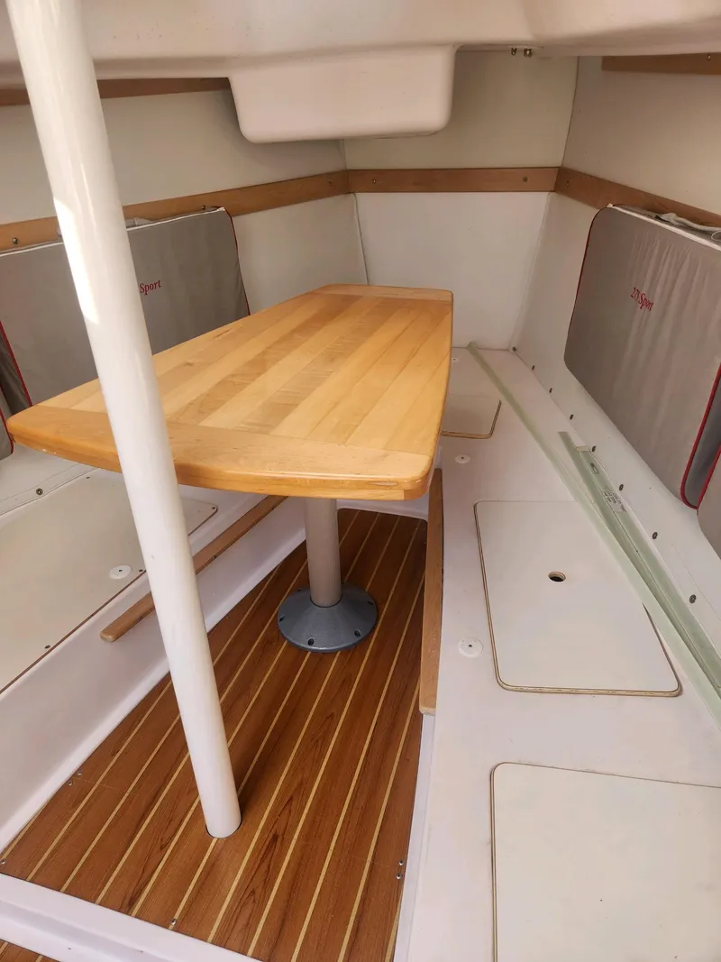 Slide: The Image of Interior of a 2015 Catalina 275 Sport with a wooden table and benches. - 19