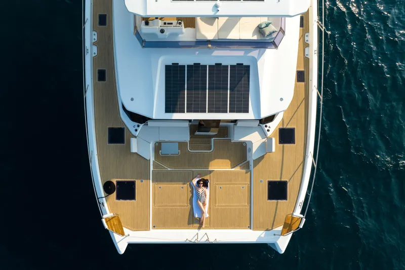 Slide: The Image of Aerial view of 2025 Omaya 50 Power Catamaran with solar panels and person relaxing on deck. - 9
