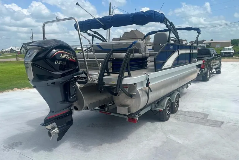 Slide: The Image of 2023 Bennington 23 SX pontoon boat with Yamaha engine on trailer, parked outdoors. - 3