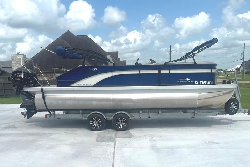 Slide: The Image of 2023 Bennington 23 SX pontoon boat on trailer, parked in residential driveway. - 4