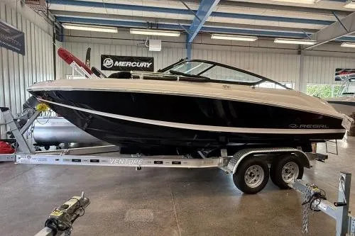 The Image of 2027 Regal 2000 ES boat on trailer in showroom, featuring sleek black and white design. - 1
