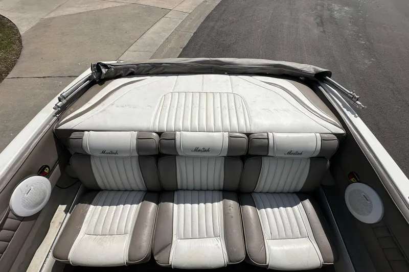 Slide: The Image of 1995 Mariah 180 Shabah boat interior with white and gray seating, parked on pavement. - 6