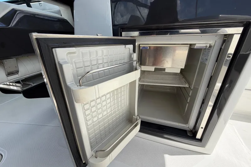 Slide: The Image of Open refrigerator on 2015 Monterey 288SS Super Sport boat, showcasing interior storage space. - 26