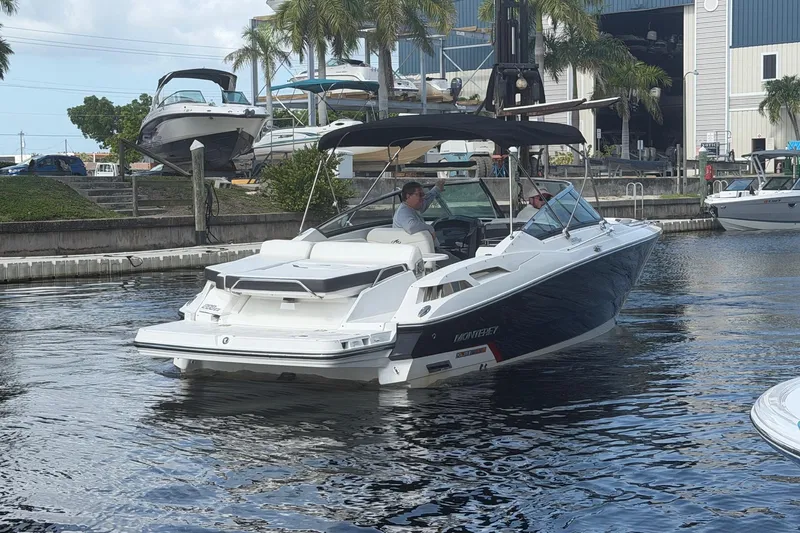 Slide: The Image of 2015 Monterey 288SS Super Sport boat cruising in a marina with palm trees and docks. - 2
