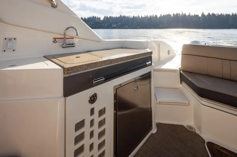 Slide: The Image of Luxurious 2016 Sea Ray SLX 350 boat interior with kitchenette and seating, overlooking serene water. - 21