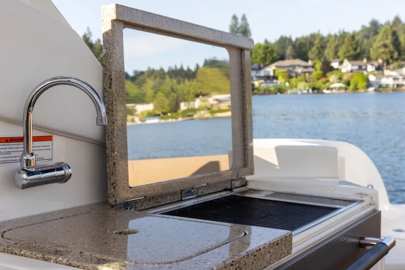 Slide: The Image of Outdoor kitchen on 2016 Sea Ray SLX 350 boat with sink and grill by the lake. - 22