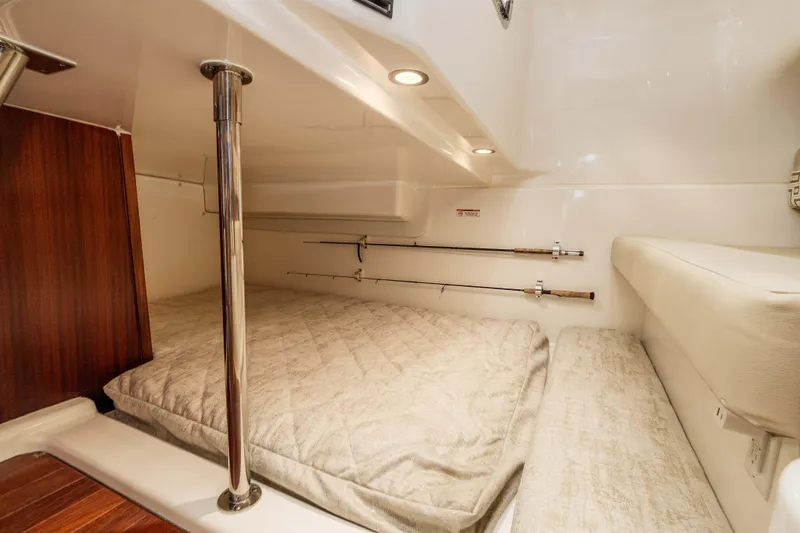 Slide: The Image of 2022 Pursuit OS 385 Offshore cabin interior with fishing rods and cozy bedding. - 32