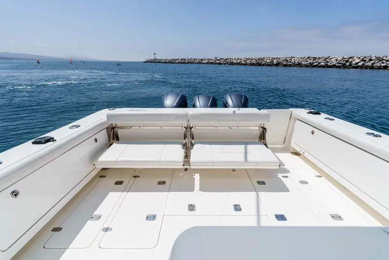 Slide: The Image of 2022 Pursuit OS 385 Offshore boat with spacious deck and triple engines on open water. - 11