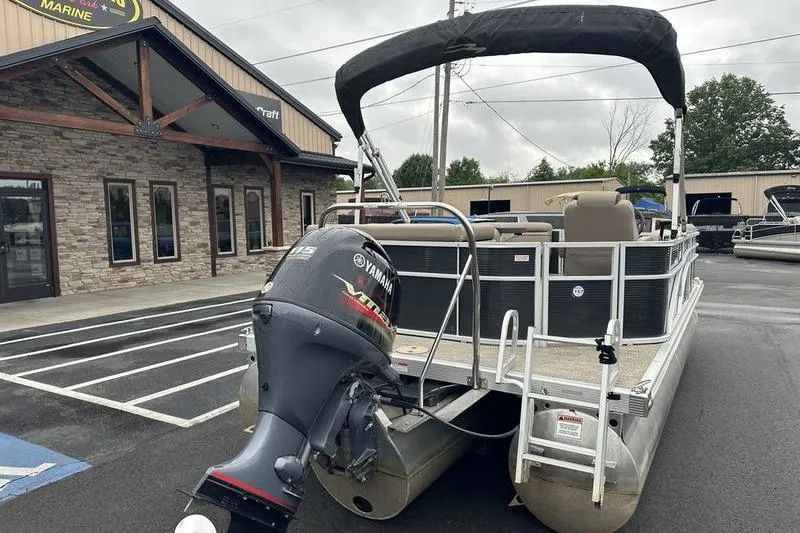Slide: The Image of 2019 Bennington 20 SLM pontoon boat with Yamaha engine, parked outside a marine dealership. - 20