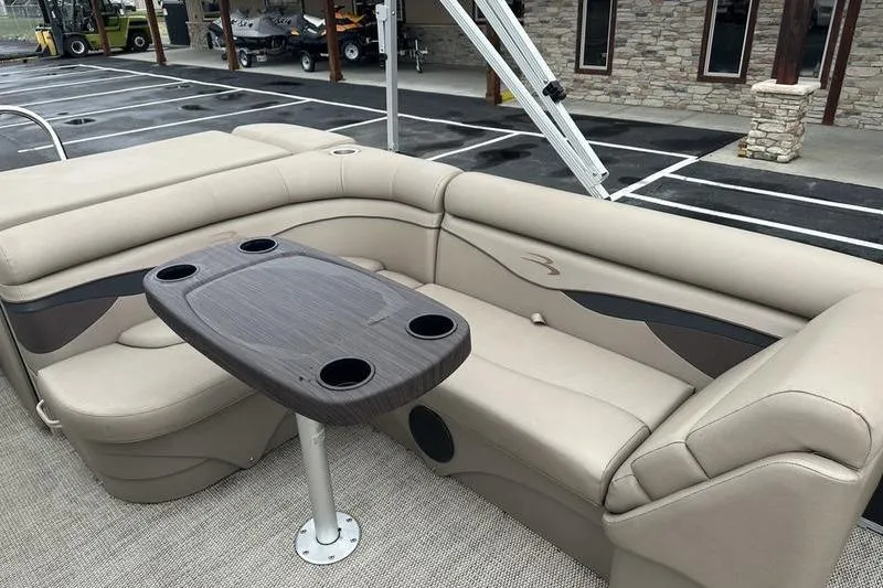Slide: The Image of 2019 Bennington 20 SLM pontoon boat interior with beige seating and a central table. - 15