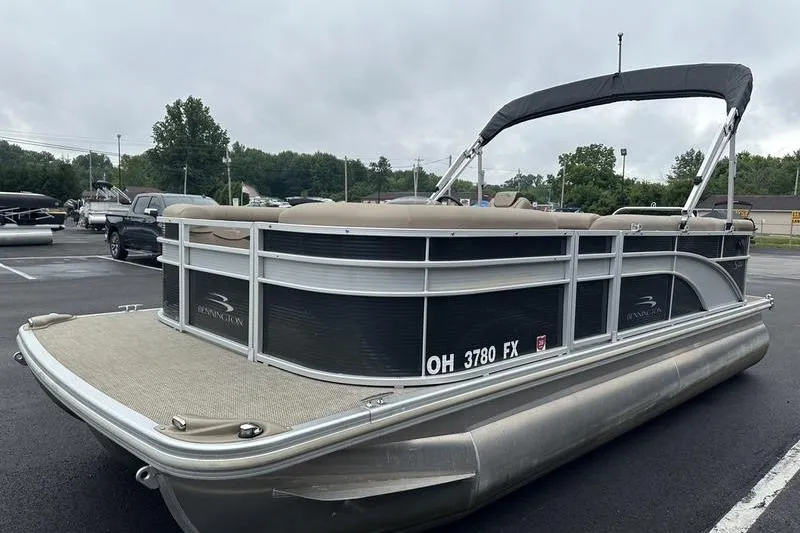 Slide: The Image of 2019 Bennington 20 SLM pontoon boat with canopy, parked on asphalt, overcast sky. - 12