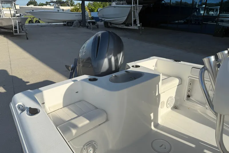 Slide: The Image of 2015 Sea Hunt Triton 225 boat interior with seating and motor, parked outdoors. - 13