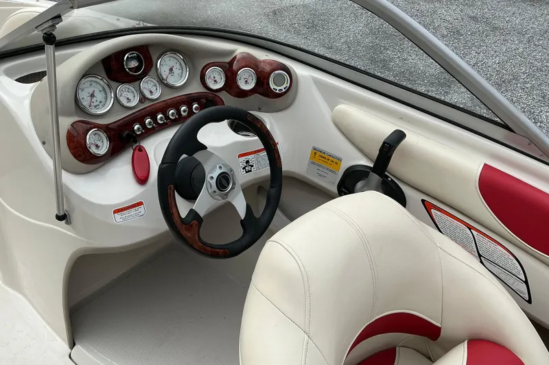 Slide: The Image of 2014 Tahoe Q7i boat dashboard with gauges, steering wheel, and red-accented seating. - 4