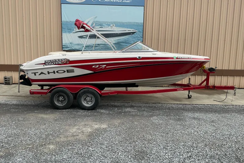 The Image of 2014 Tahoe Q7i boat on trailer, red and white design, parked outdoors. - 0