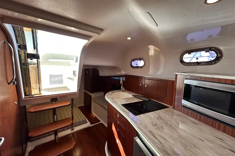 Slide: The Image of Interior of 2018 Pursuit OS 385 Offshore boat with modern kitchen and wooden cabinetry. - 16