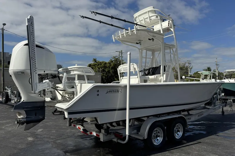Slide: The Image of 2018 Jupiter 25 Bay boat on trailer, featuring dual engines and fishing tower. - 2