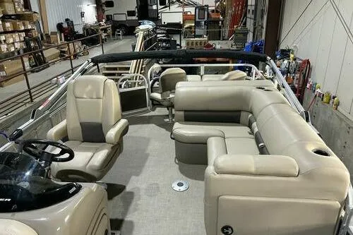 Slide: The Image of 2022 Sun Tracker SportFish 22 XP3 pontoon boat interior with beige seating in a warehouse. - 6