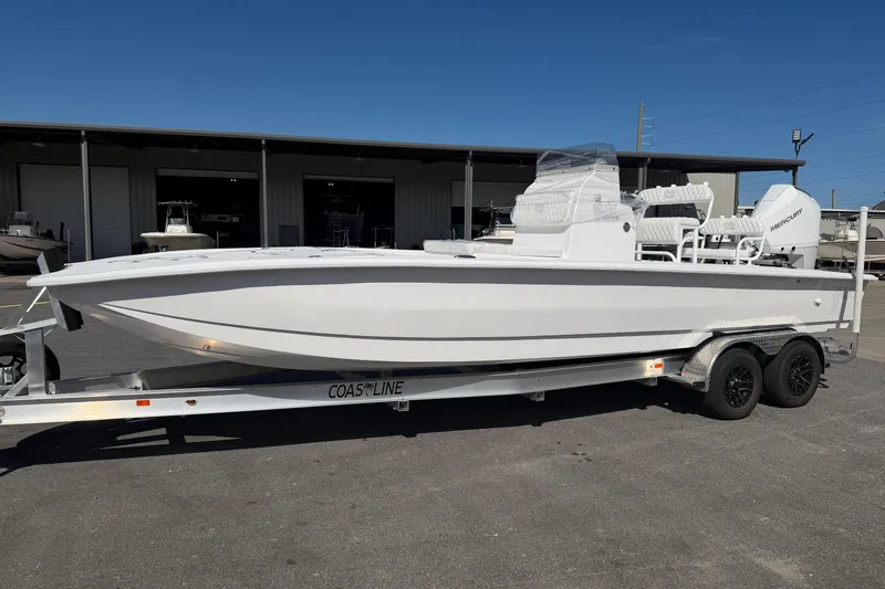 Slide: The Image of 2026 Skuta 24 Cat boat on trailer, parked outdoors under clear blue sky. - 4