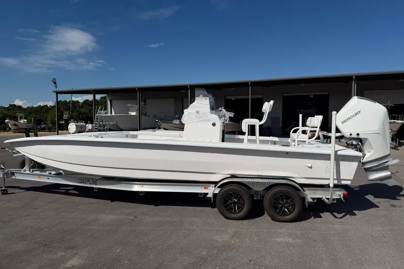 Slide: The Image of 2026 Skuta 24 Cat boat on trailer, featuring Mercury outboard motor, parked outdoors. - 5