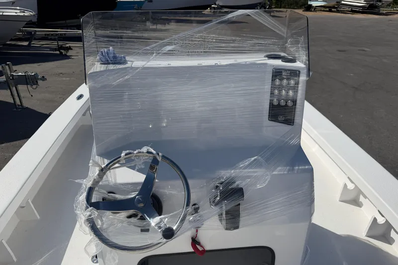 Slide: The Image of 2026 Skuta 24 Cat boat console wrapped in protective plastic, featuring steering wheel and controls. - 31
