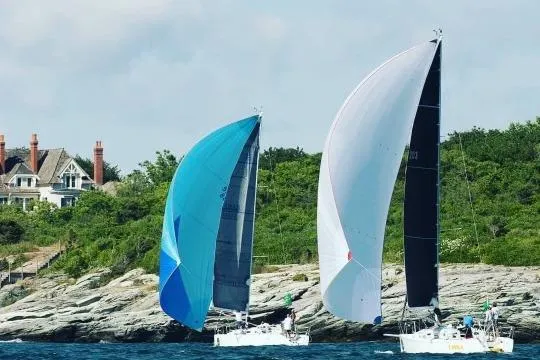 Slide: The Image of Two J/109 sailboats racing near a rocky shoreline, 2004 model. - 26