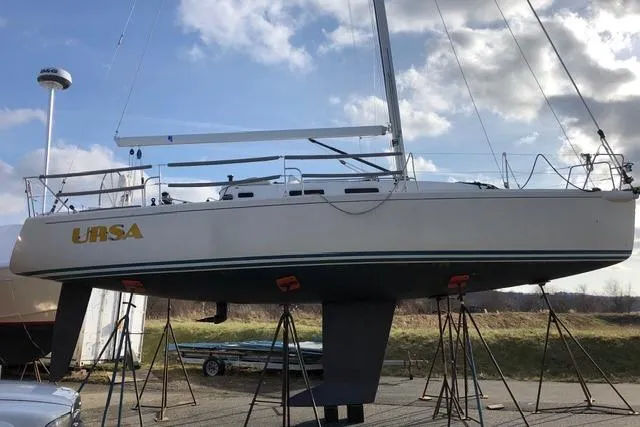 Slide: The Image of 2004 J Boats J/109 sailboat on stands, named "URSA," under a partly cloudy sky. - 25