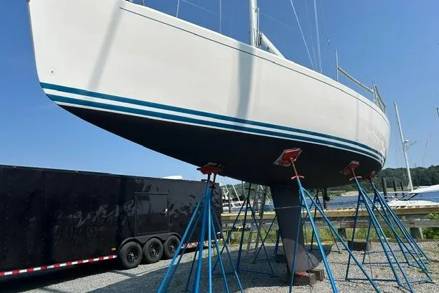 Slide: The Image of 2004 J Boats J/109 sailboat on stands, with blue stripes, in a boatyard. - 24