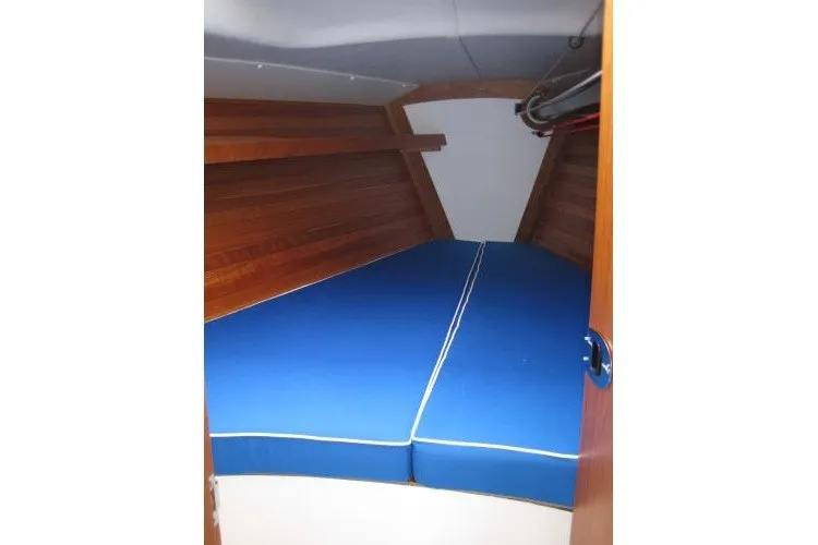 Slide: The Image of 2005 J Boats J/109 interior cabin with blue cushions and wooden paneling. - 28