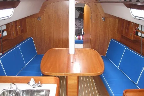 Slide: The Image of Interior of 2005 J Boats J/109 sailboat with wooden table and blue seating. - 25