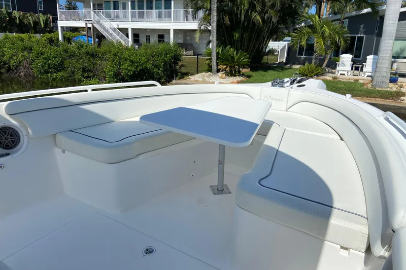 Slide: The Image of 2017 Stamas 317 Tarpon boat with white seating and table, docked near lush greenery. - 49