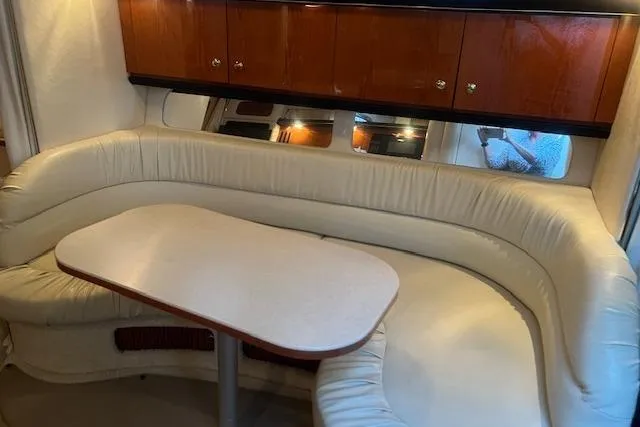 Slide: The Image of Interior of 2001 Sea Ray 340 Sundancer with curved seating and wooden cabinets. - 9