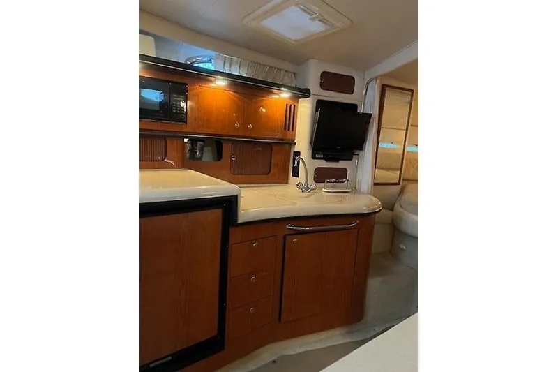 Slide: The Image of 2001 Sea Ray 340 Sundancer interior with kitchenette, wood cabinets, and TV. - 12