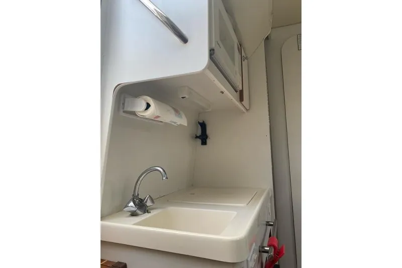 Slide: The Image of Interior of a 1996 Pursuit 3000 Offshore boat featuring a compact sink and storage area. - 11