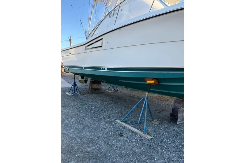 Slide: The Image of 1996 Pursuit 3000 Offshore boat on stands, displayed on gravel surface. - 18