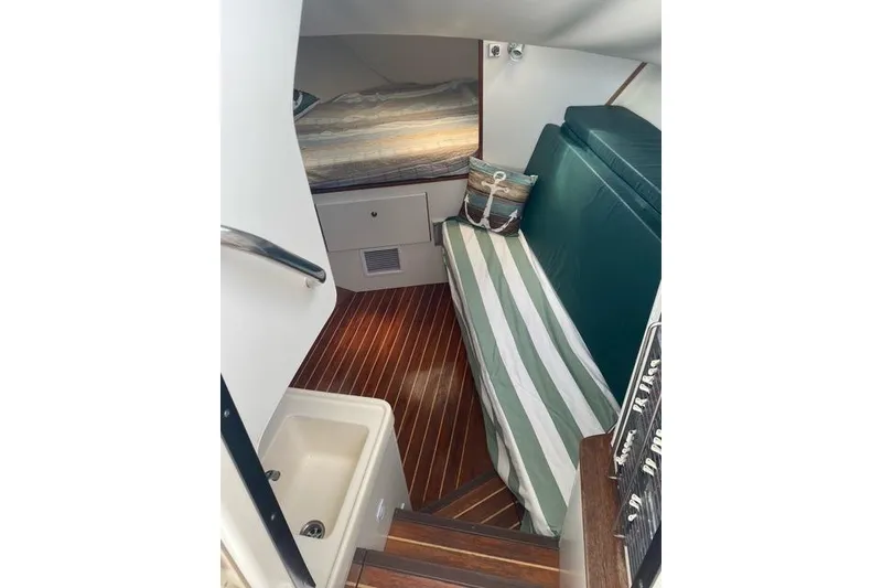 Slide: The Image of Interior of a 1996 Pursuit 3000 Offshore boat with striped seating and wooden flooring. - 7
