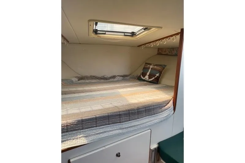 Slide: The Image of Cozy cabin interior of a 1996 Pursuit 3000 Offshore boat with a skylight and anchor-themed pillow. - 8