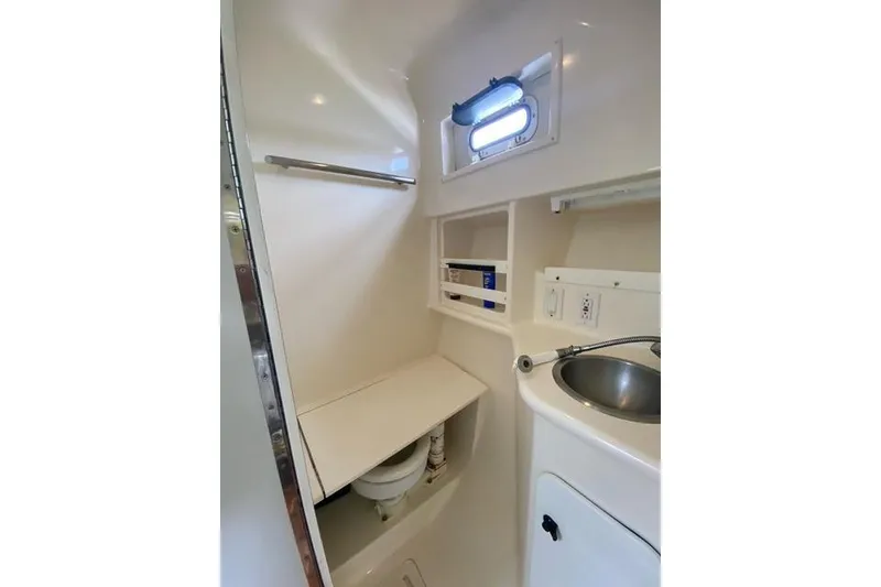 Slide: The Image of Interior of 1996 Pursuit 3000 Offshore boat bathroom with sink and porthole. - 14